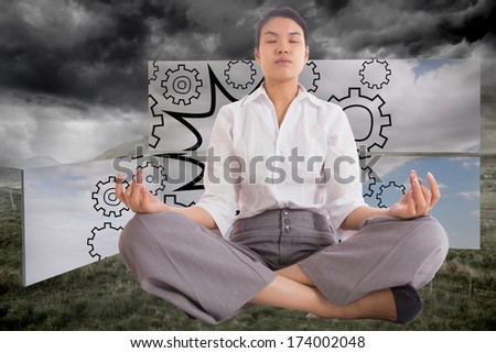 Businesswoman sitting in lotus pose against stormy countryside background