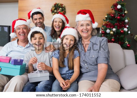 Portrait Of Extended Family In Christmas Hats With Gift Boxes In The Living Room At Home