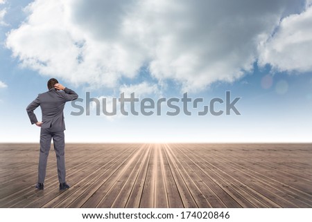 Thinking businessman scratching head against cloudy sky background