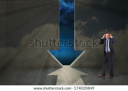 Stressed businessman with hands on head against arrow door in dark room