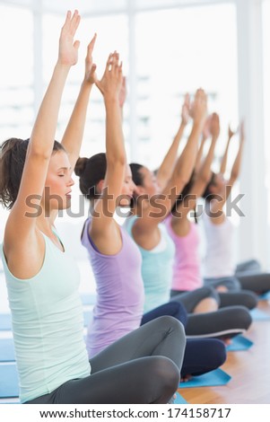 Side view of sporty young women in meditation pose with eyes closed at a bright fitness studio