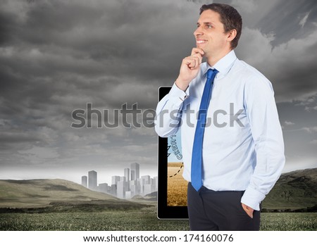 Thinking businessman touching his chin against cityscape in distance under cloudy sky