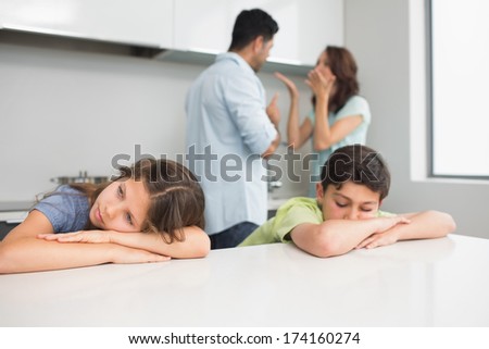 Sad young kids while parents quarreling in the kitchen at home