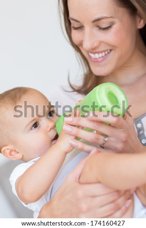 Closeup of a mother feeding baby with milk bottle at home