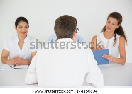 Panel of business people conducting job interview with male candidate