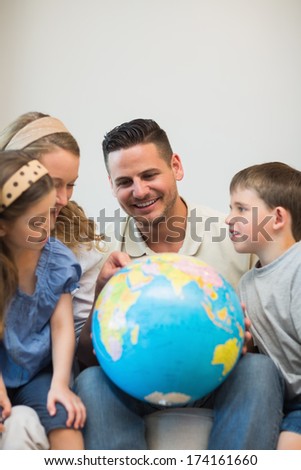 Happy family eploring places on globe in house
