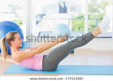 Full length side view of a sporty young woman stretching body in fitness studio