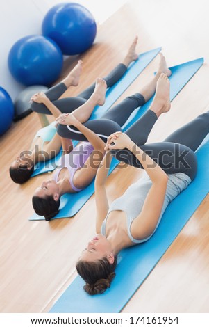 Full length of sporty young people stretching legs in fitness studio