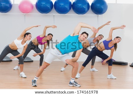 Instructor and fitness class doing stretching exercise in fitness studio