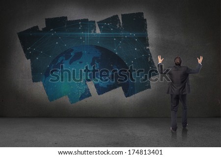 Gesturing businessman against display on wall showing global technology graphic