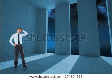 Thoughtful businessman with hand on head against light shining into dark room