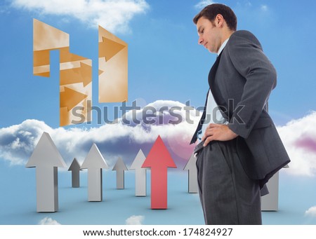 Stern businessman standing with hands on hips against red and grey arrows pointing up against sky