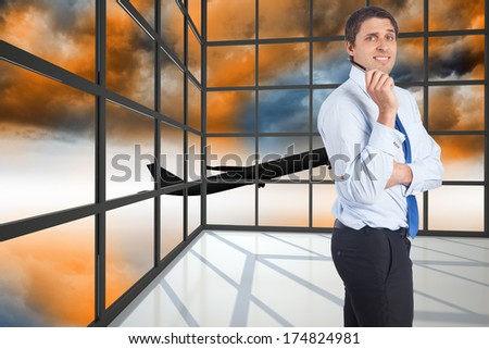 Thinking businessman holding pen against airplane flying over orange sky past window