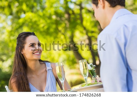 Smiling young couple with champagne flutes sitting at an outdoor cafÃ?Â©