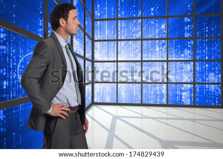 Serious businessman with hand on hip against glowing key seen through window