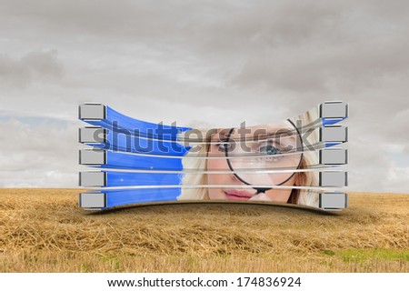 Blonde with magnifying glass on abstract screen against cloudy countryside background