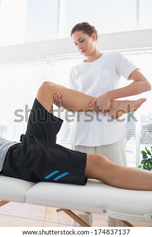 Physical therapist massaging leg of man at health spa
