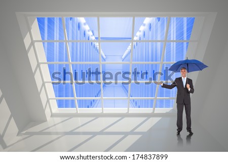 Peaceful businessman holding blue umbrella against server hallway seen through window
