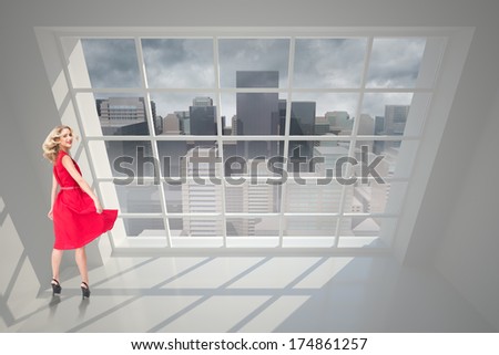 Smiling blonde turning against cityscape seen through window