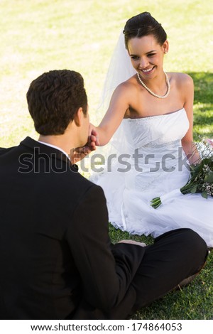 View of a groom kissing his beautiful bride\'s hand at the park