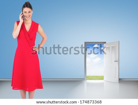 Cheerful elegant brunette in red dress on the phone posing against door opening showing blue sky