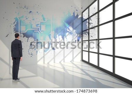 Businessman turning his back to camera against splash showing technology interface