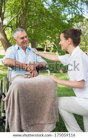 Woman with her mature father sitting in wheel chair at the park