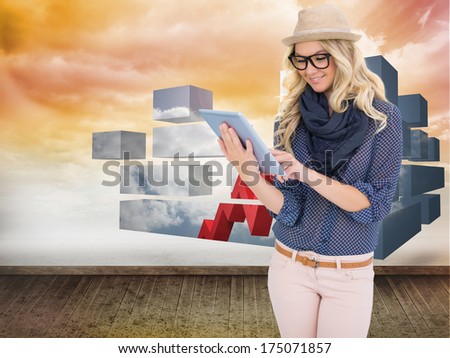 Smiling trendy blonde using tablet computer against orange sky on wall