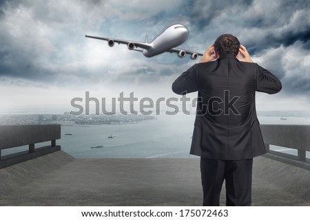 Stressed businessman with hands on head against coastline and city
