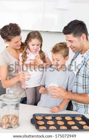 Cheerful family having cookies and milk at home in kitchen