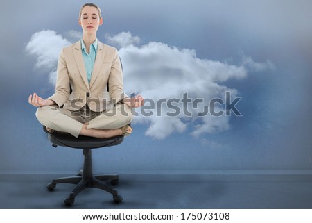 Peaceful chic businesswoman sitting in lotus position on swivel chair against clouds in a room