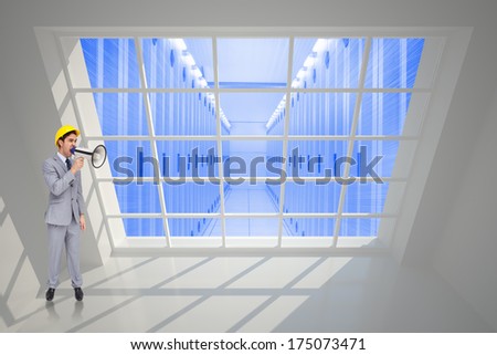 Young architect yelling with a megaphone against server hallway seen through window