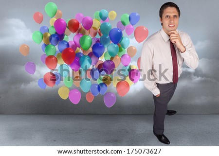 Thinking businessman touching his chin against many colourful balloons in cloudy room