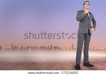 Thinking businessman with hand on chin against cityscape on the horizon
