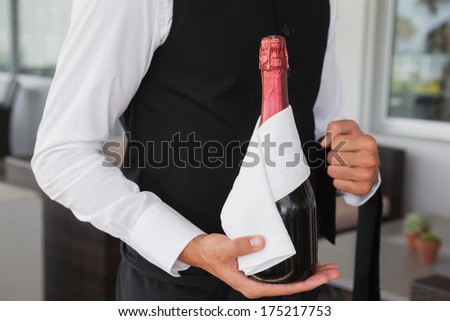 Well dressed waiter holding magnum of champagne in the patio of restaurant