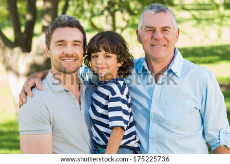 Grandfather father and son smiling against blurred background at the park