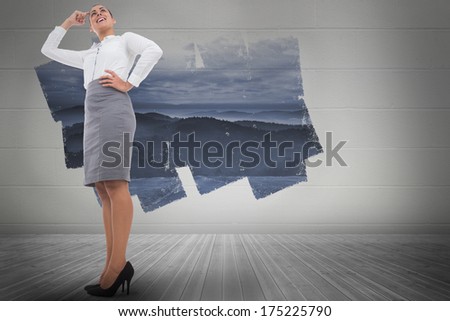 Smiling thoughtful businesswoman against display on wall showing mountain landscape