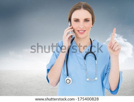 Pretty woman doctor phoning and pointing with her finger against cloudy sky background