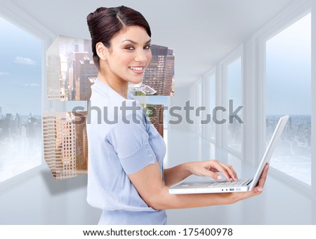 Cheerful businesswoman using a laptop against bright white hall with windows