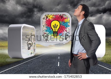 Serious businessman with hand on hip against stormy landscape background with street