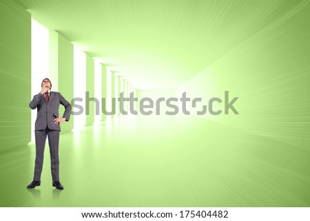 Thinking businessman touching chin against bright green room with windows