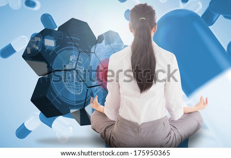 Businesswoman sitting in lotus pose against blue pills floating