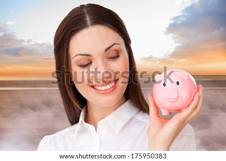 Confident businesswoman holding a piggybank against peaceful scene