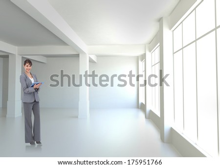 Smiling businesswoman with tablet computer against white room with windows