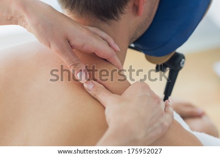 Closeup of man receiving shoulder massage by therapist in hospital