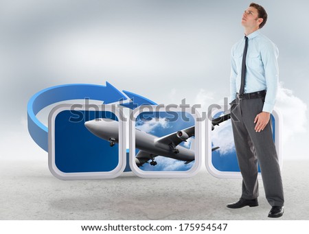 Serious businessman standing with hand in pocket against blue arrow in a desert landscape