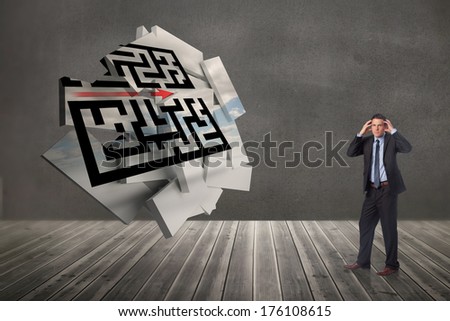 Stressed businessman with hands on head against maze graphic on abstract screen in room