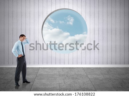 Thoughtful businessman with hand on head against window showing blue sky