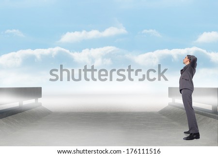 Thinking businessman scratching head against road leading out to the horizon