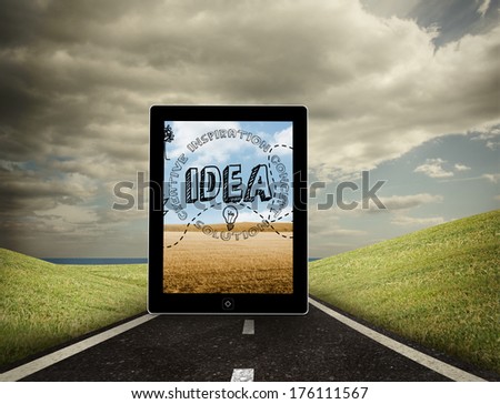 Idea graphic on tablet screen against highway under cloudy sky